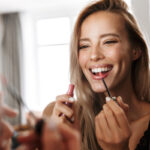 Woman applying lipstick seeing the mirror