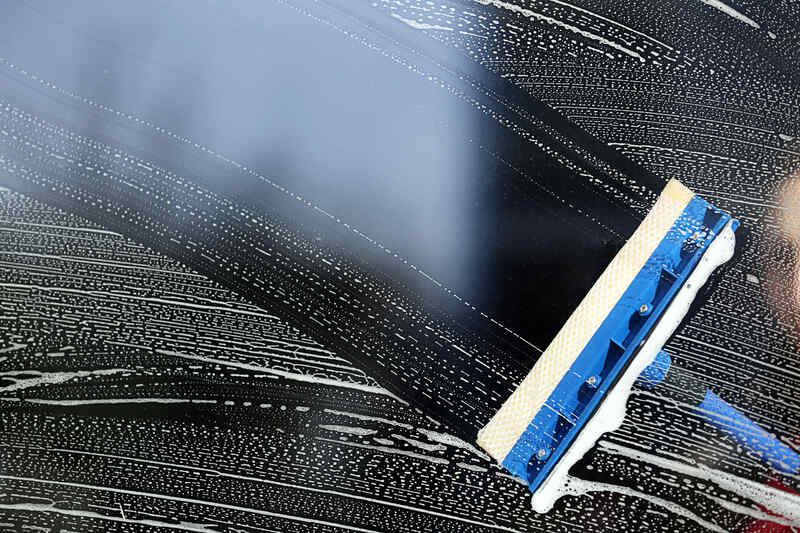 Cleaning a glass with a squeegee, close up
