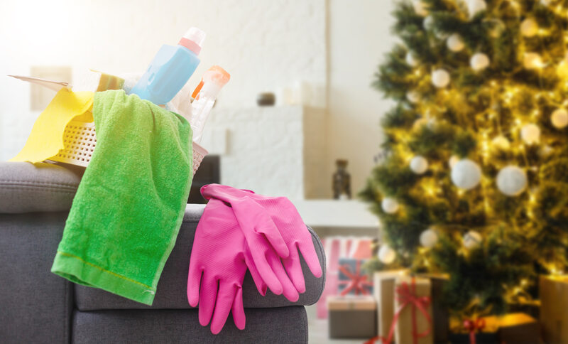 Cleaning before Christmas. Multicolored cleaning supplies. Sponges, rags and spray with festive decorations against modern home background.