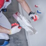 How Much Does Drywall Installation Cost in 2026? person doing a drywall patching job