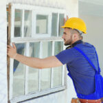 How Much Does Window Replacement Cost in 2026? Worker removing old window in a flat