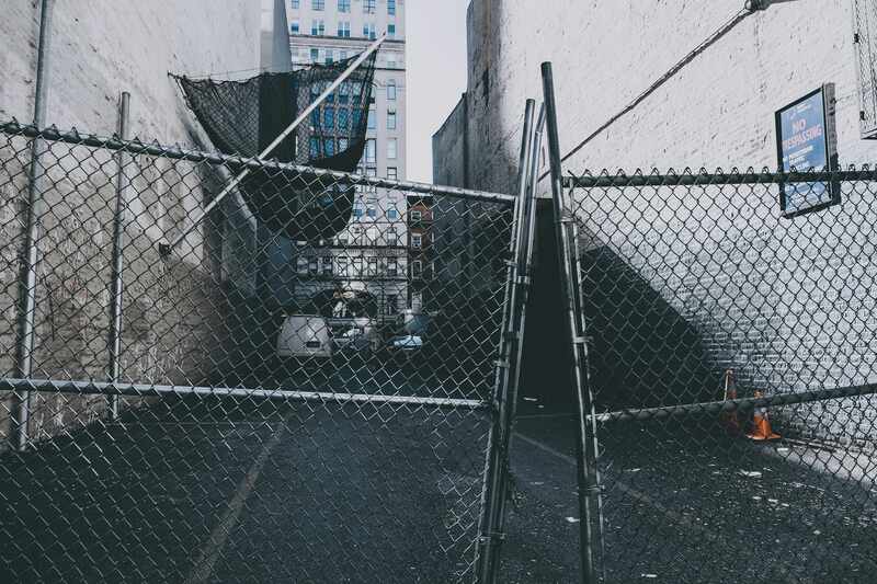 A broken chain link gate in an alleyway