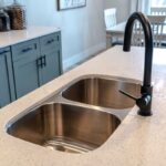 Stainless steel undermount double basin kitchen island sink with black faucet.