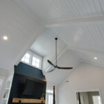 Bright and Inviting Living Room with Vaulted White Shiplap Ceiling, Cozy Fireplace, and Large Windows for Abundant Natural Light