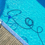 How Much Does Pool Cleaning Cost in Florida? Man cleaning the swimming pool with vacuum equipment.
