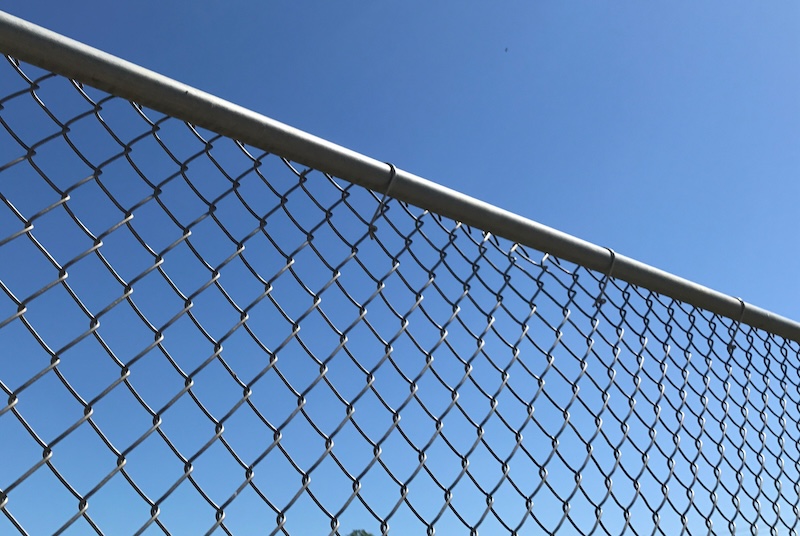 Closeup of a metal chain link fence top rail