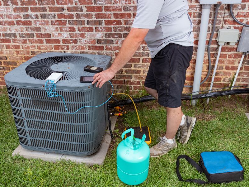 Air Conditioner maintenance with technician adding refrigerant 
