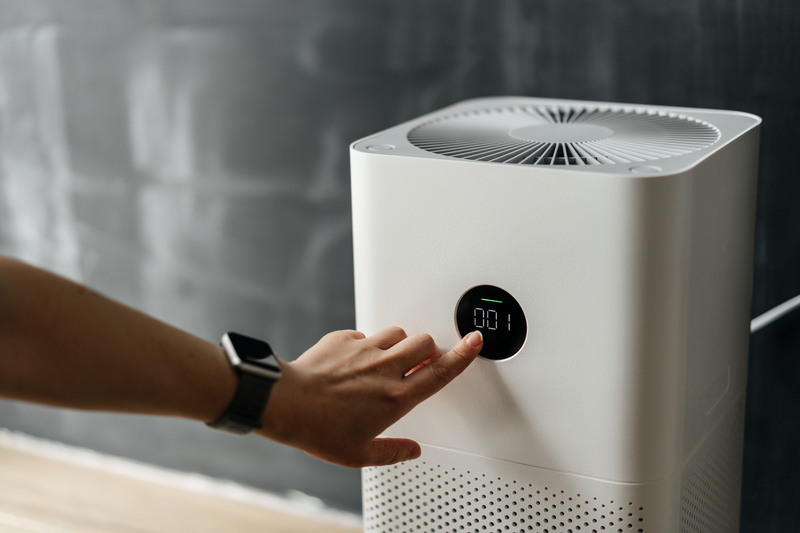A woman's hand presses the touch screen button to start an air purifier.