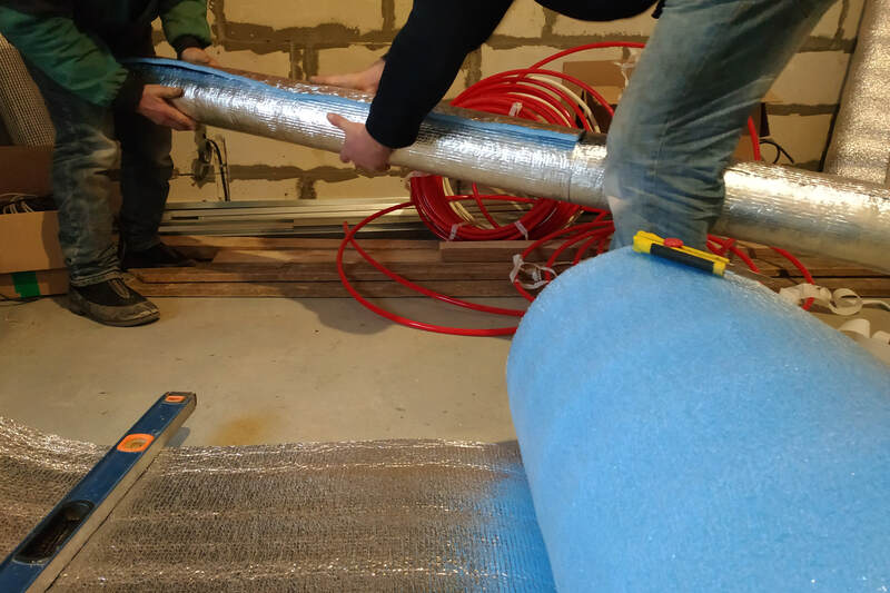 workers wrapping air duct with mineral wool and foil