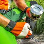 Gardener installing outdoor light in a residential garden during daytime