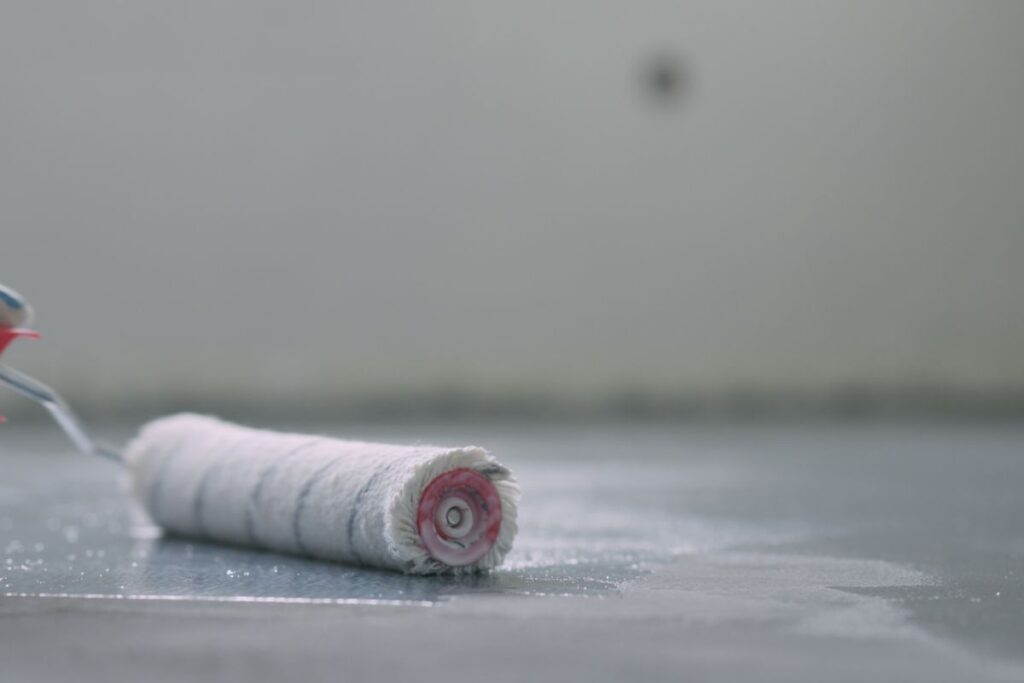 closeup of applying protective coating on a concrete floor using a paint roller