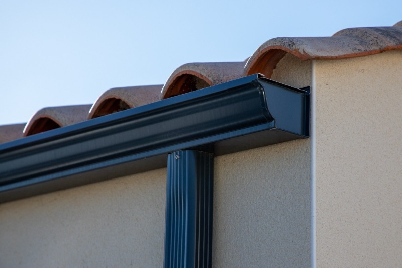 Close-up view of a K-style gutter system attached to a house with a tiled roof