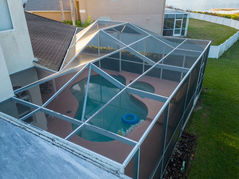 Patio and pool enclosed by a screen enclosure with aluminum beams  
