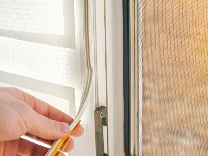 A man glues a sealing rubber tape on it for noise insulation, wind protection, weather protection.