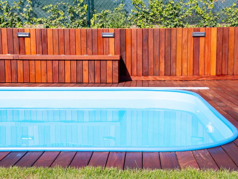 Swimming pool with stained wooded deck and fence
