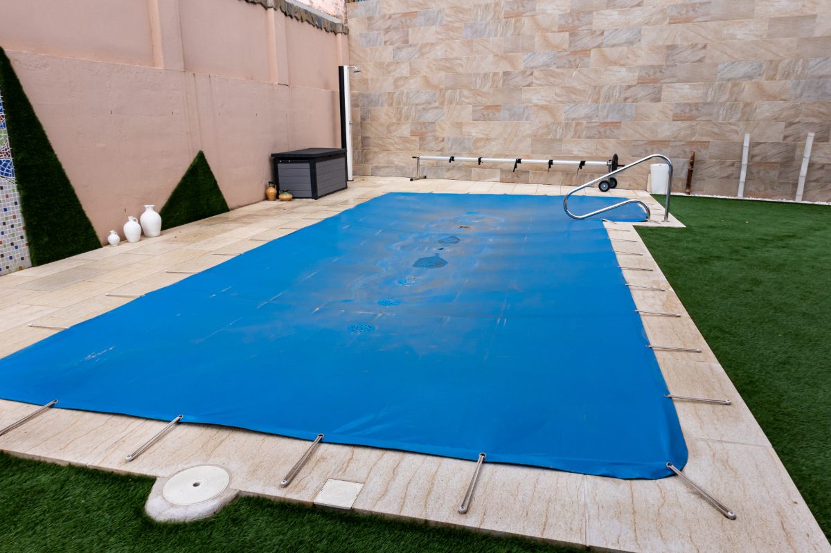 Small pool covered with a blue tarpaulin during the winter season to cover it and prevent dirt