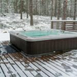 Steaming hot tub in the snow, illustrating a spa being used or maintained during the winter months.