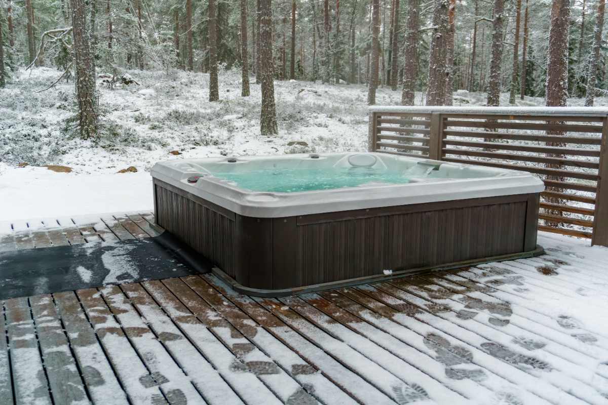Steaming hot tub in the snow, illustrating a spa being used or maintained during the winter months.