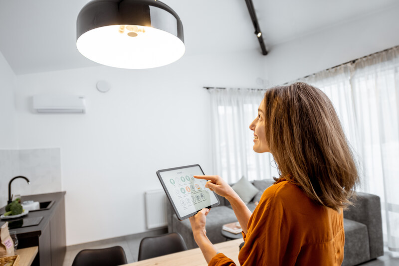 Woman controlling a smart home lighting system using a digital tablet with a home automation interface.